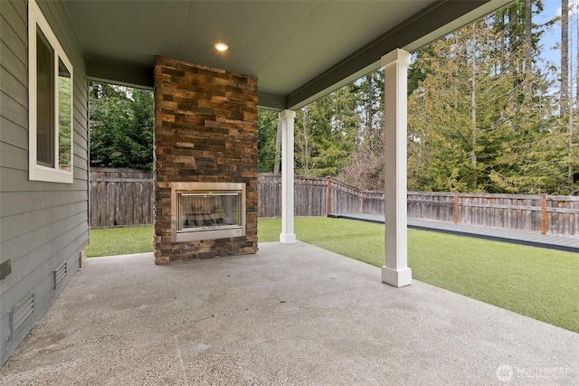 view of patio / terrace with an outdoor stone fireplace and a fenced backyard