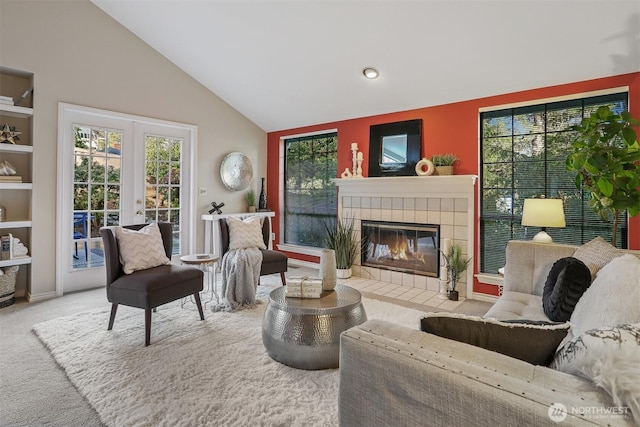 sitting room featuring vaulted ceiling, french doors, a tiled fireplace, and carpet flooring