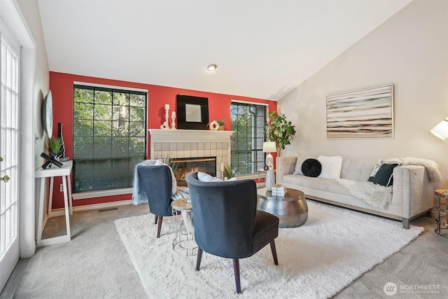 living room featuring carpet floors, a wealth of natural light, lofted ceiling, visible vents, and a tile fireplace