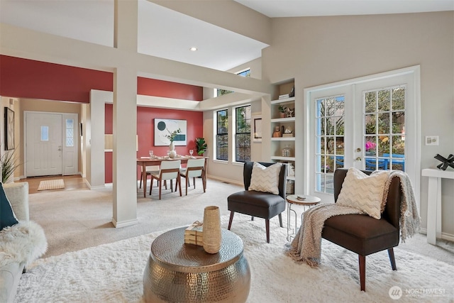 sitting room with high vaulted ceiling, french doors, light colored carpet, and baseboards