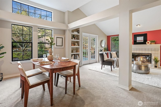 carpeted dining room with high vaulted ceiling, french doors, a healthy amount of sunlight, and a fireplace