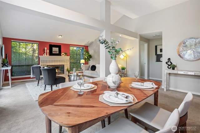 dining area with carpet, a healthy amount of sunlight, a fireplace, and lofted ceiling