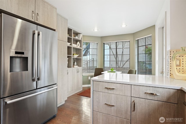 kitchen with dark wood-style flooring, stainless steel refrigerator with ice dispenser, open shelves, light countertops, and a peninsula