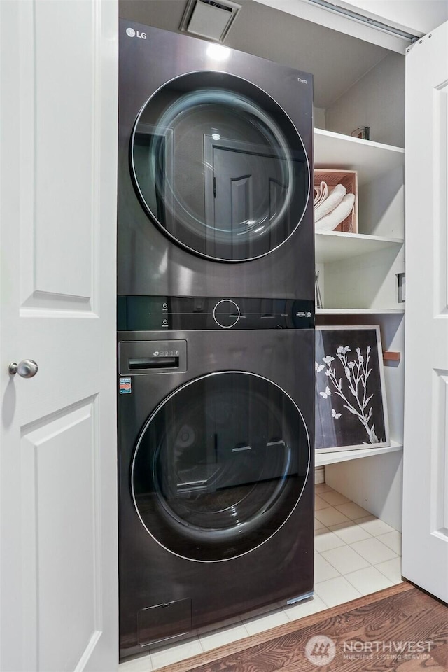 laundry room with laundry area, stacked washer / dryer, visible vents, and tile patterned floors