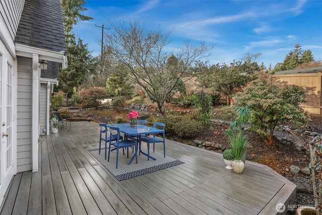 wooden terrace with outdoor dining space and fence