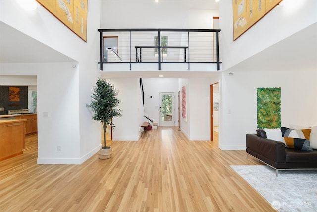 foyer featuring a high ceiling, stairs, light wood-type flooring, and baseboards