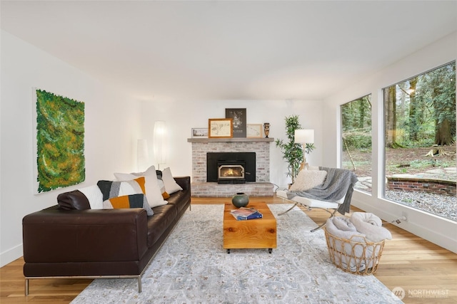 living area with a fireplace, baseboards, and wood finished floors