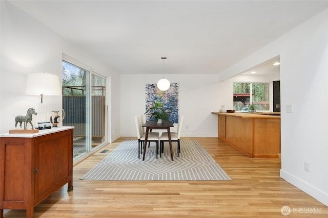 dining area featuring light wood finished floors, visible vents, and baseboards