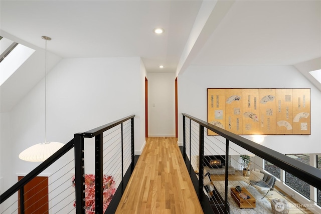 corridor featuring recessed lighting, an upstairs landing, light wood-style floors, and vaulted ceiling with skylight