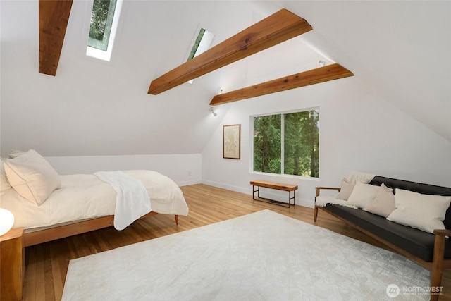 bedroom featuring vaulted ceiling with skylight, wood finished floors, and baseboards