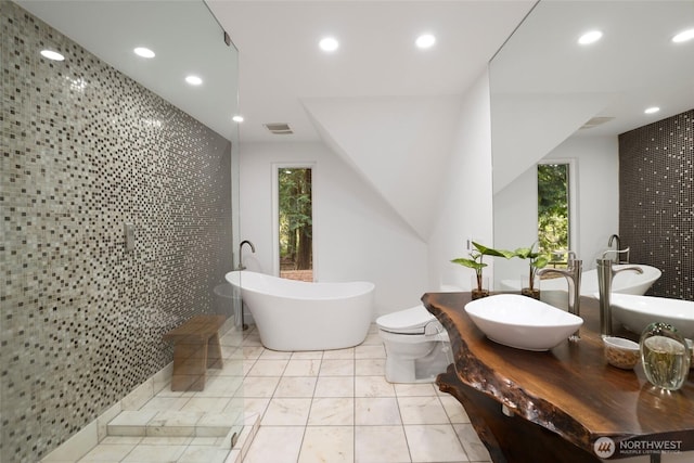 full bath featuring visible vents, recessed lighting, tiled shower, a freestanding tub, and tile walls