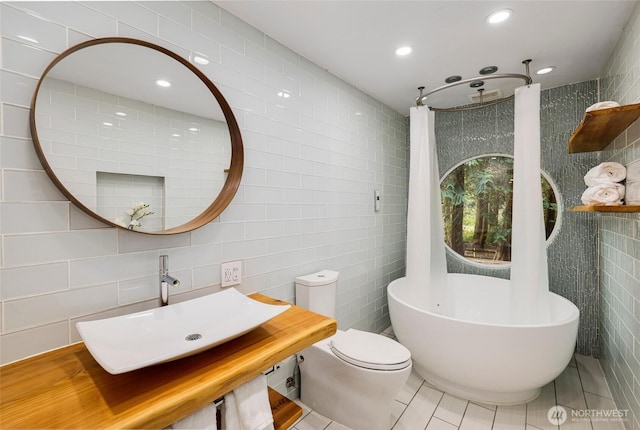 full bathroom with recessed lighting, a freestanding bath, a sink, tile patterned floors, and toilet