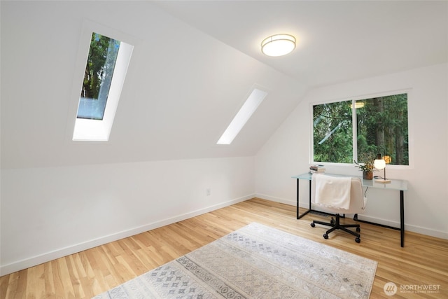 office area with lofted ceiling with skylight, wood finished floors, and baseboards