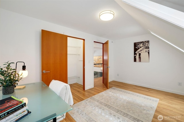 office space featuring baseboards, lofted ceiling, and wood finished floors