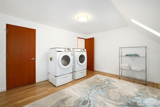 laundry room with laundry area, a skylight, wood finished floors, and washer and clothes dryer