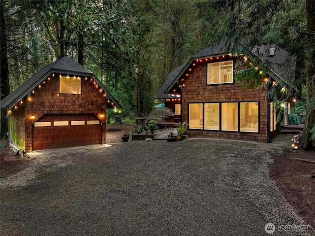 chalet / cabin with a wooded view, an outbuilding, a garage, and roof with shingles