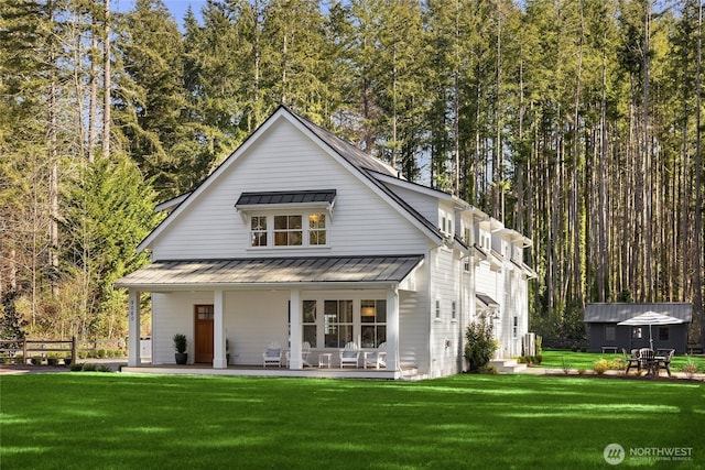 back of house featuring a standing seam roof, a lawn, and metal roof