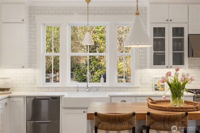 kitchen featuring a sink, light countertops, white cabinets, glass insert cabinets, and dishwasher