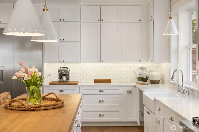 kitchen with tasteful backsplash, wooden counters, and white cabinetry