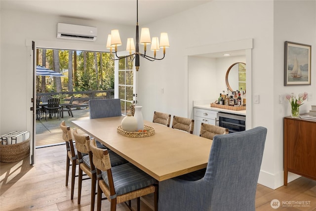 dining room with a wall mounted air conditioner, a bar, an inviting chandelier, and light wood-style flooring