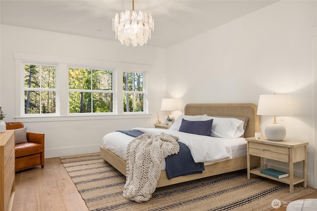 bedroom with a notable chandelier, wood finished floors, and baseboards