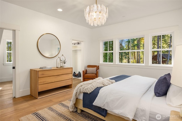 bedroom with recessed lighting, multiple windows, a notable chandelier, and light wood-style flooring