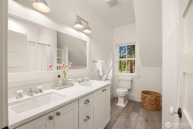 full bath with visible vents, toilet, wood finished floors, and a sink