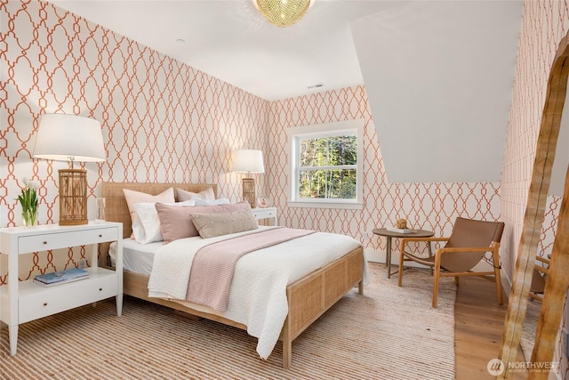 bedroom featuring visible vents, wood finished floors, and wallpapered walls