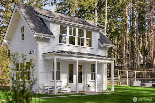 view of front of home with a shingled roof, a front lawn, covered porch, metal roof, and a standing seam roof