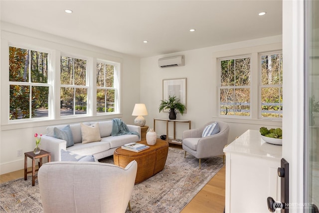 living room with a wall unit AC, recessed lighting, light wood-type flooring, and baseboards