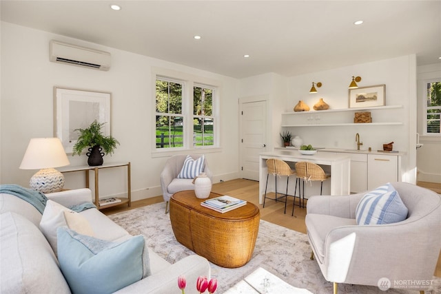 living area featuring a wall unit AC, plenty of natural light, and light wood finished floors