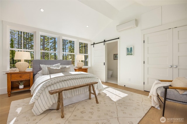 bedroom with lofted ceiling, recessed lighting, a wall mounted air conditioner, a barn door, and light wood-type flooring