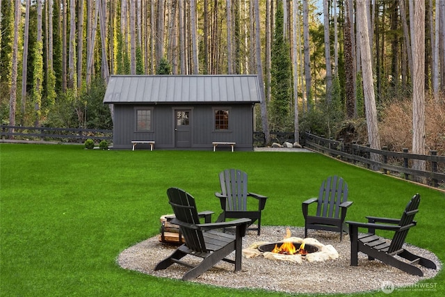 view of yard featuring an outbuilding, an outdoor fire pit, and fence