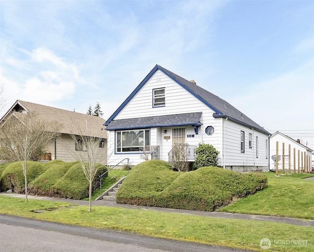 view of front of house with a front lawn and a shingled roof