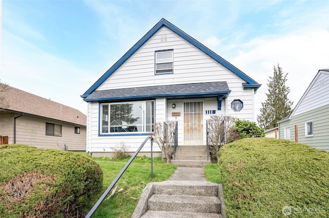 bungalow-style house featuring roof with shingles and a front lawn