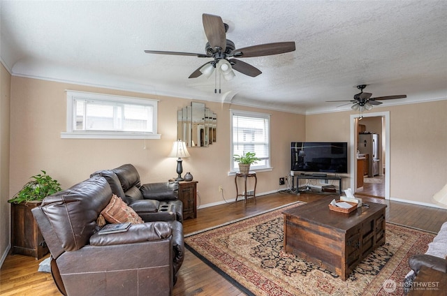 living room with hardwood / wood-style flooring, crown molding, baseboards, and a textured ceiling