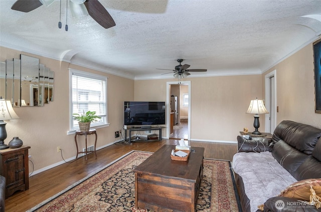 living room with a textured ceiling, wood finished floors, and ornamental molding