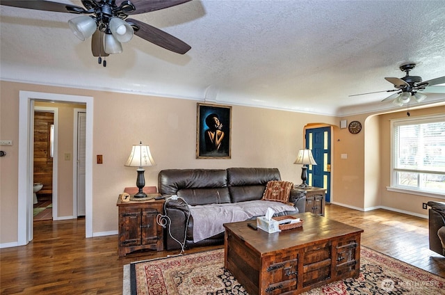 living room with ceiling fan, hardwood / wood-style flooring, arched walkways, and a textured ceiling