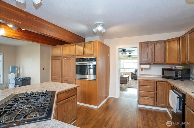 kitchen featuring black appliances, light countertops, dark wood-type flooring, and brown cabinets