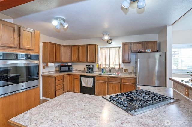 kitchen with a sink, brown cabinets, black appliances, and light countertops