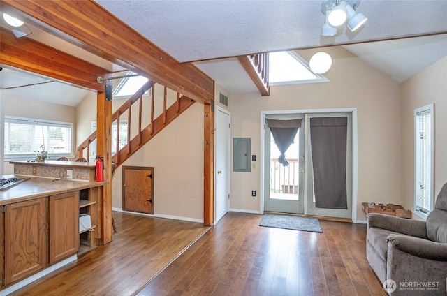 foyer entrance featuring electric panel, stairs, wood finished floors, and vaulted ceiling with beams