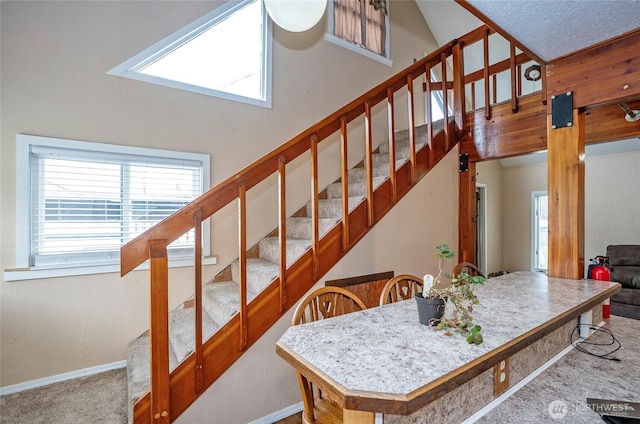 stairs with carpet, baseboards, and high vaulted ceiling