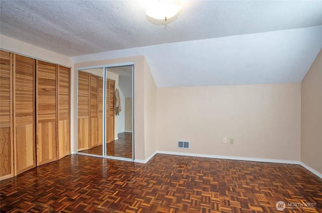 bonus room featuring visible vents, a textured ceiling, baseboards, and vaulted ceiling