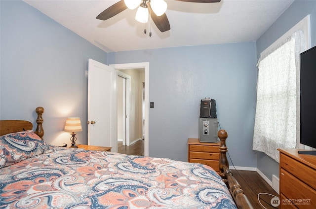 bedroom with a ceiling fan, dark wood-type flooring, and baseboards