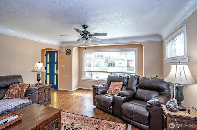 living area with a textured ceiling, ornamental molding, and hardwood / wood-style flooring