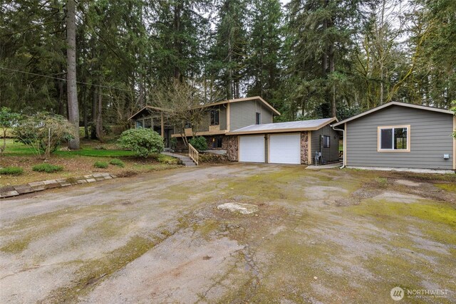 view of front of home with stone siding, driveway, and an attached garage