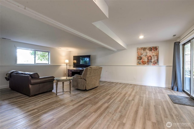 living area featuring beamed ceiling, baseboards, and light wood finished floors