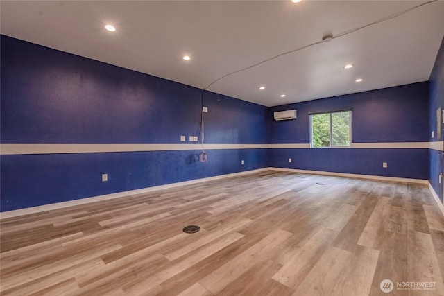 spare room with recessed lighting, baseboards, wood finished floors, and a wall unit AC