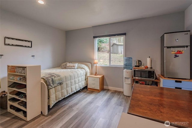 bedroom with recessed lighting, baseboards, light wood-style floors, and freestanding refrigerator