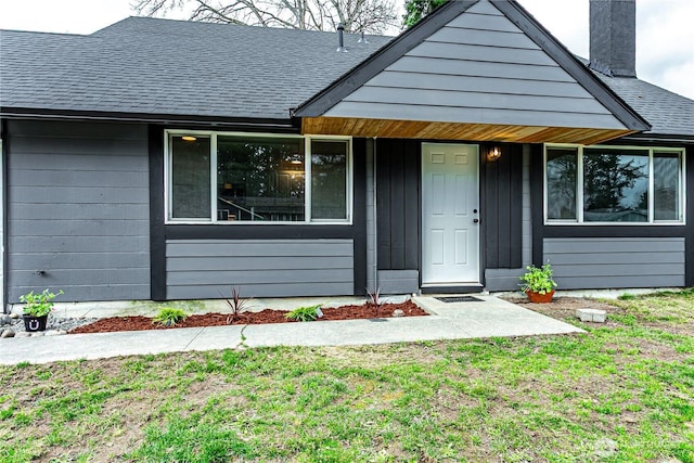 exterior space featuring a shingled roof, a chimney, and a front lawn